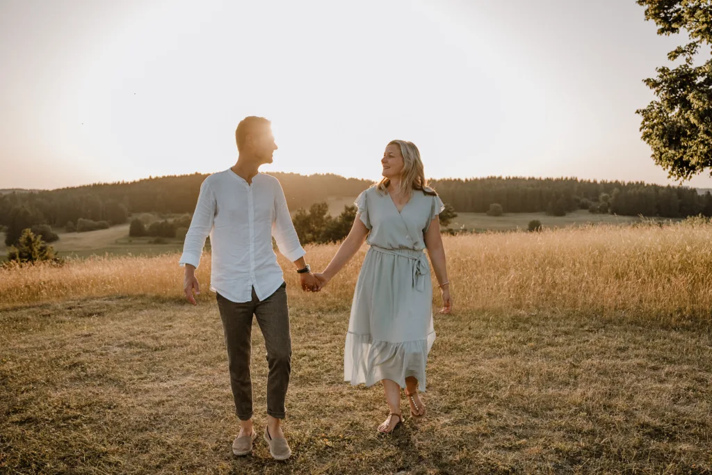 Eltern spazieren Hand in Hand bei einem natürlichen Familienshooting in der Abendsonne bei Rottweil Beschreibung: