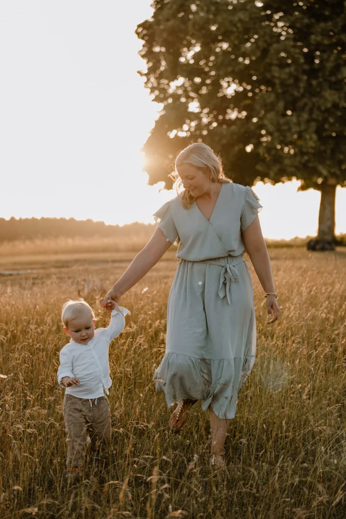 Mama spaziert mit ihrem Kleinkind bei einem natürlichen Familienshooting im warmen Abendlicht bei Rottweil