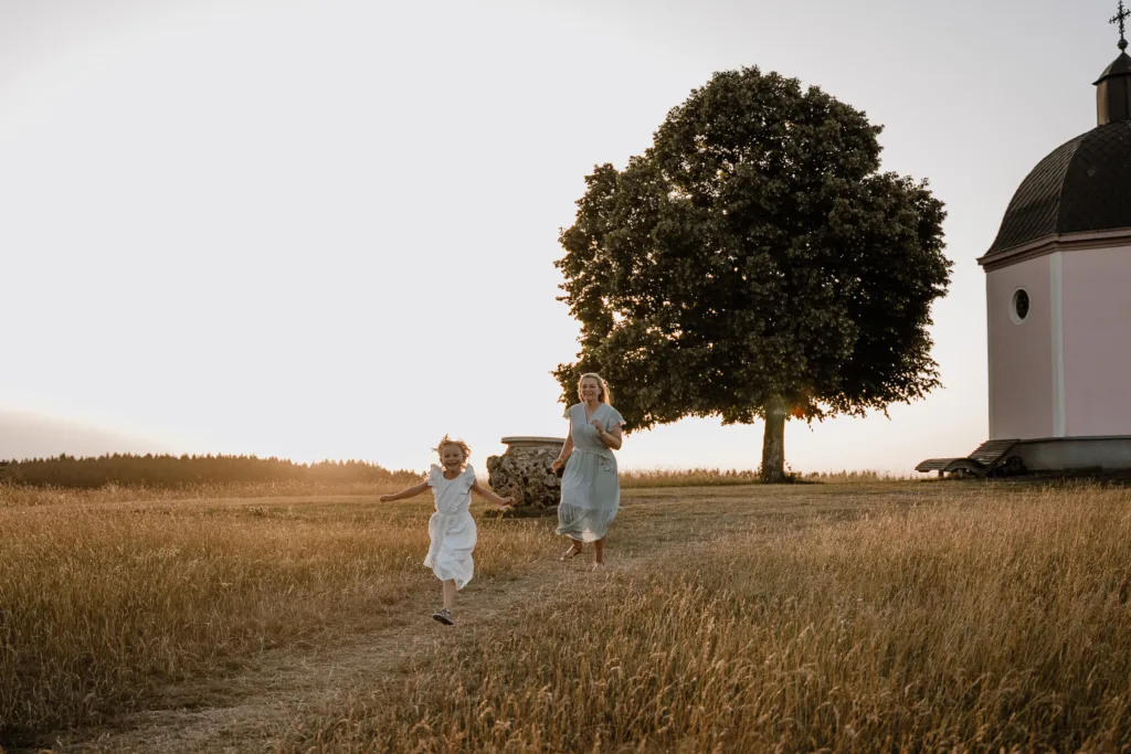 Mama und Tochter laufen gemeinsam über eine Wiese bei einem Familienshooting in der Natur bei Rottweil