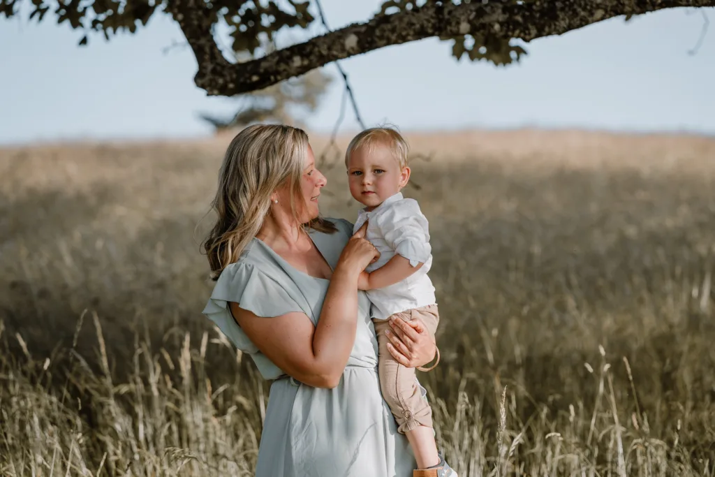 Mutter hält ihren kleinen Sohn im Arm auf einer sonnigen Wiese