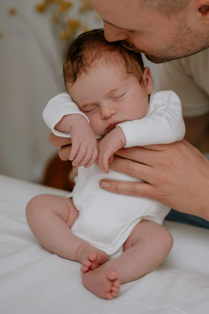 Neugeborenenshooting-Papa küsst Baby auf Kopf