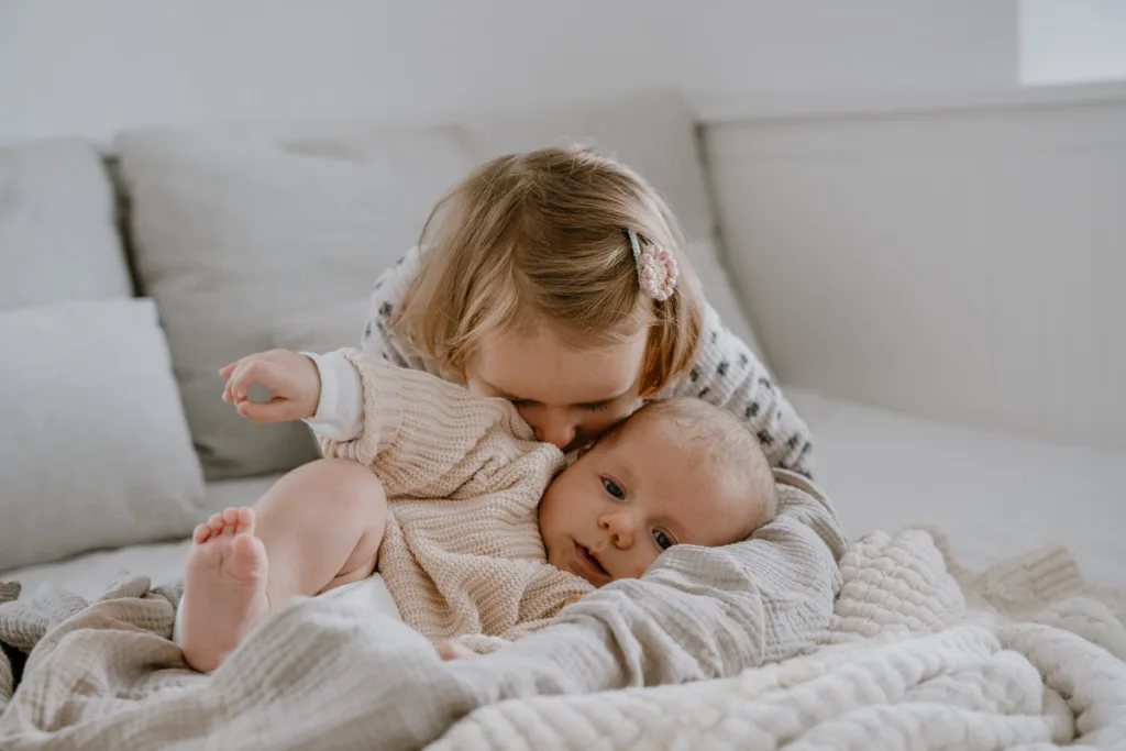 Große Schwester kuschelt innig mit dem Baby