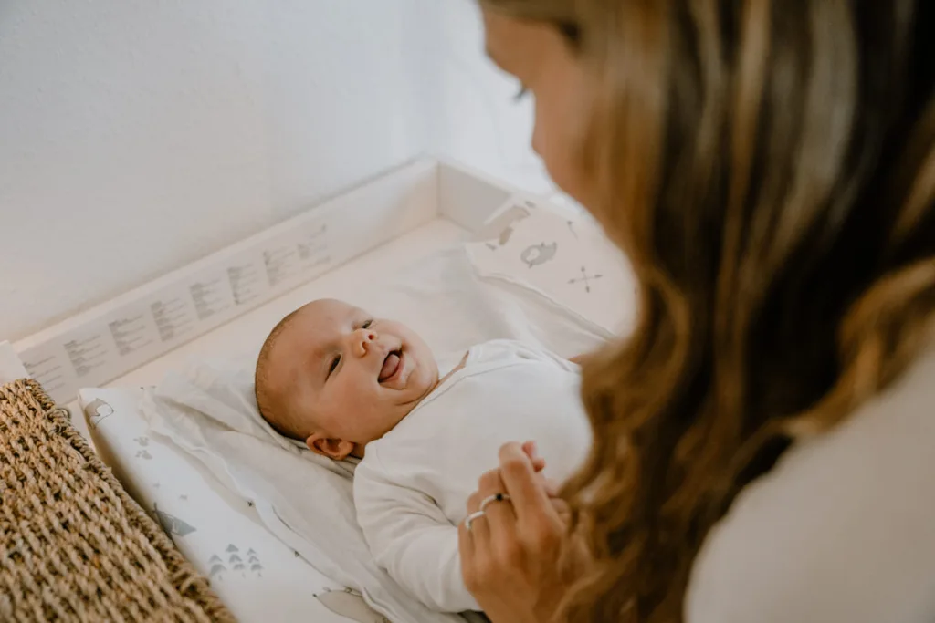 Mutter wickelt ihr Baby unter einer Wärmelampe