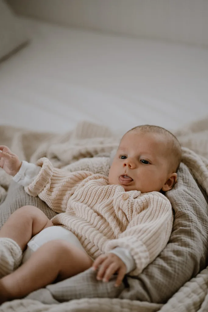 Ein Baby liegt entspannt auf weichen Decken und schaut aufmerksam in die Kamera