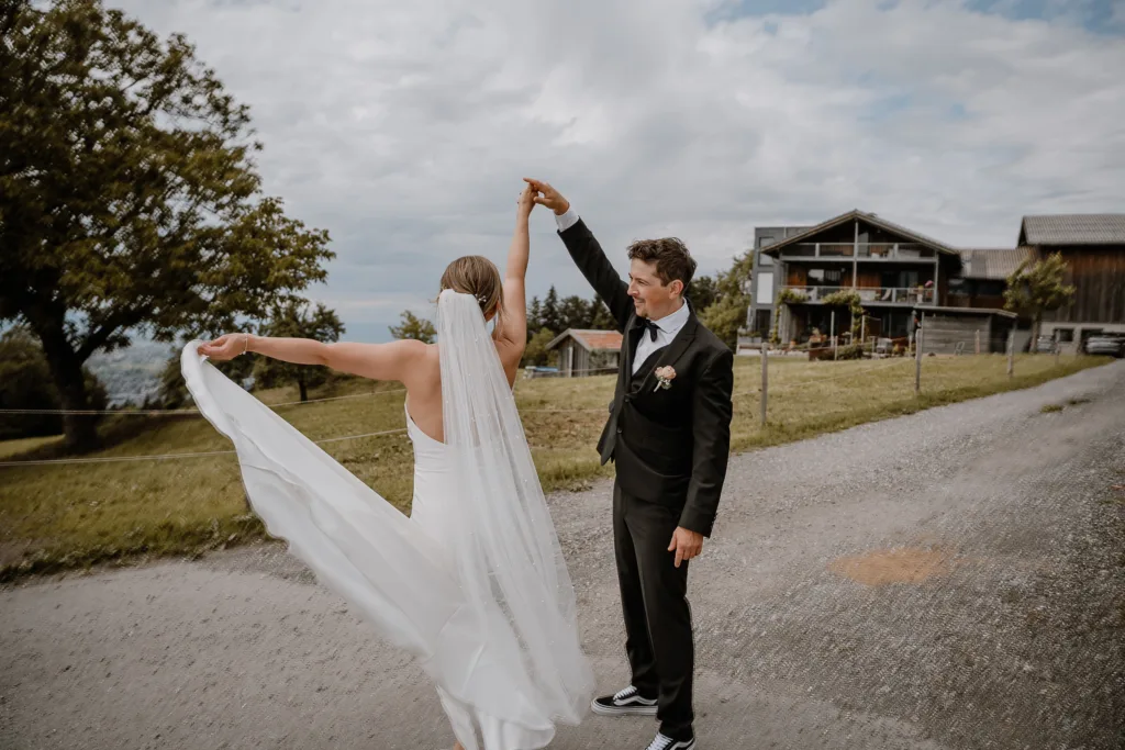 Bräutigam dreht die Braut bei einer Hochzeit in Österreich, Brautkleid weht im Wind.