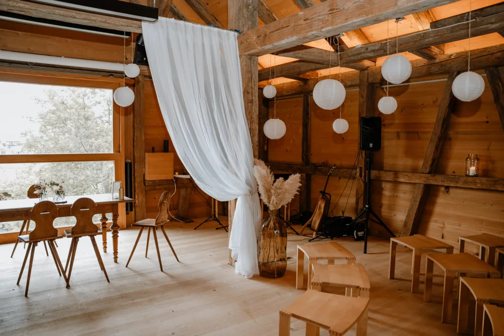 Rustikale Hochzeitslocation mit Holzstühlen und Dekoration in einer Scheune in Österreich.