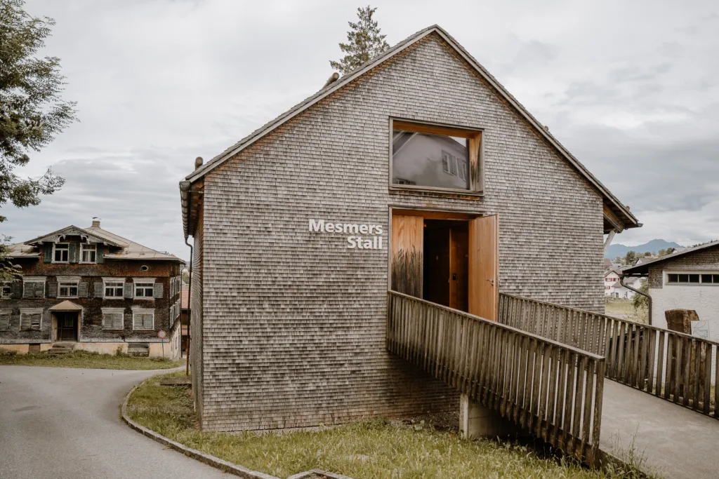 Außenansicht der Hochzeitslocation Mesmers Stall in Vorarlberg mit Holzfassade und Eingang.