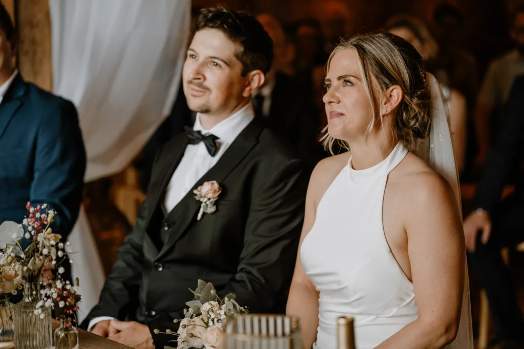 Brautpaar sitzt nebeneinander während der Trauung, hört aufmerksam zu.