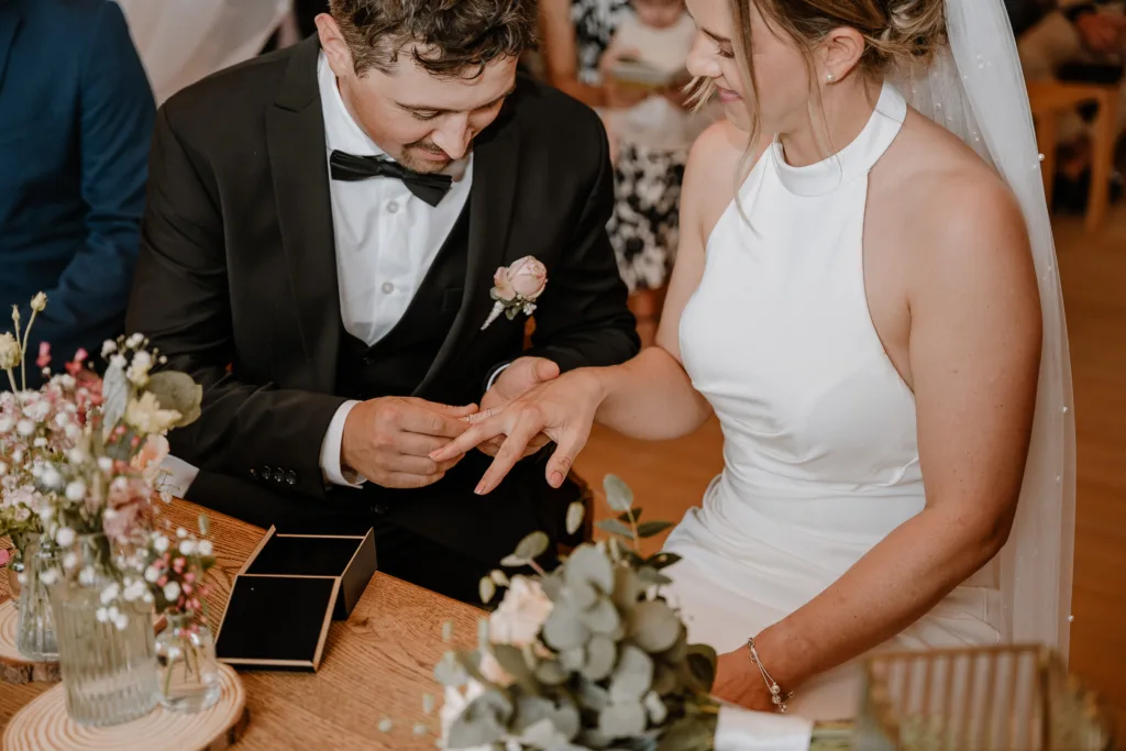 Bräutigam steckt der Braut den Ehering während der Trauung an.