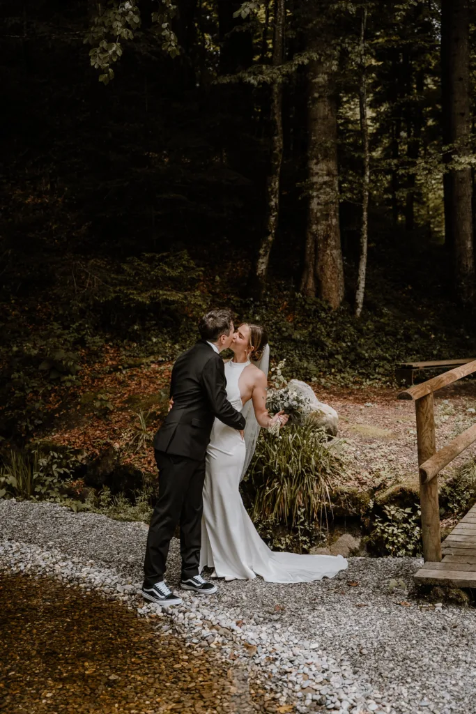 Brautpaar auf einer Holzbrücke im Wald in Österreich, romantische Hochzeitsfotos in den Bergen.