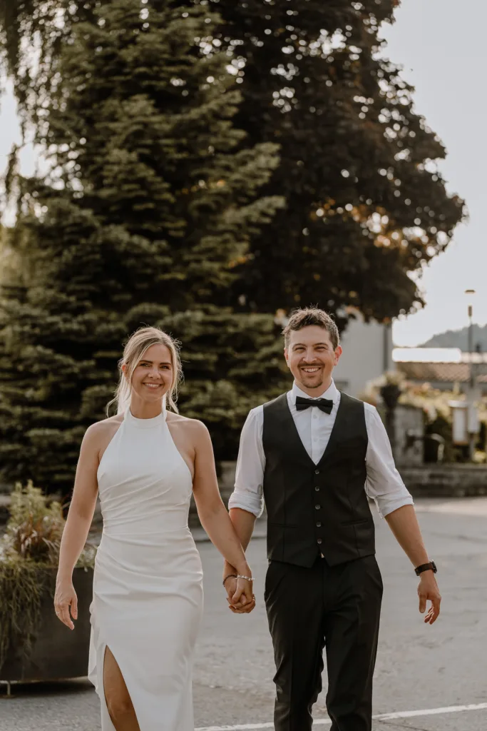 Brautpaar geht Hand in Hand über den Vorplatz der Hochzeitslocation.