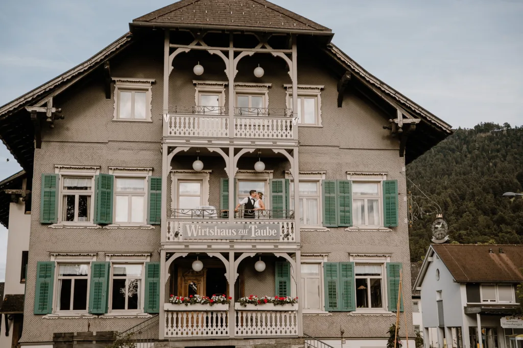 Historische Fassade des Wirtshauses zur Taube in Alberschwende mit Brautpaar auf dem Balkon.