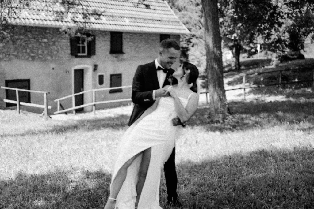 Schwarzweißfoto Brautpaar lachend und tanzend im Grünen