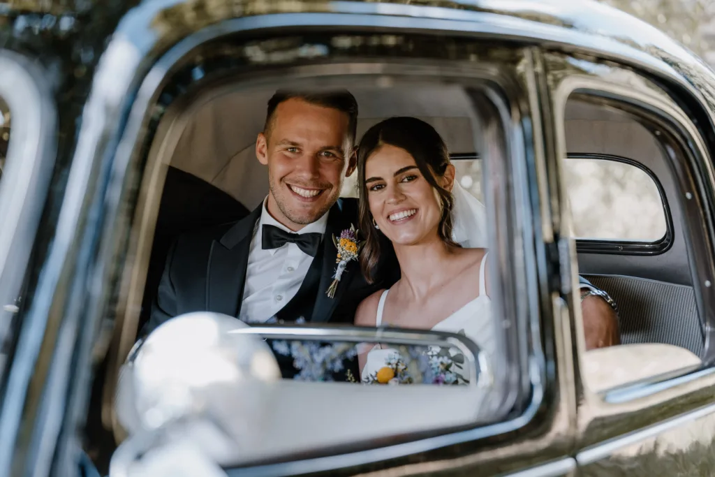 Brautpaar sitzt lächelnd im Oldtimer nach der Hochzeit in Rottweil