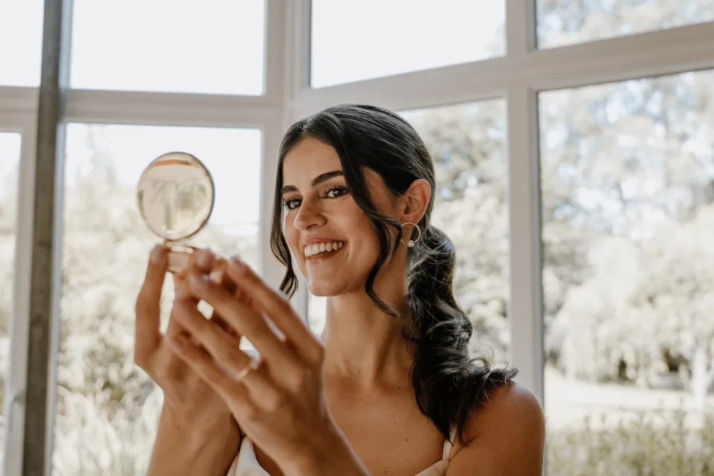 Braut betrachtet sich im Spiegel im natürlichen Licht.