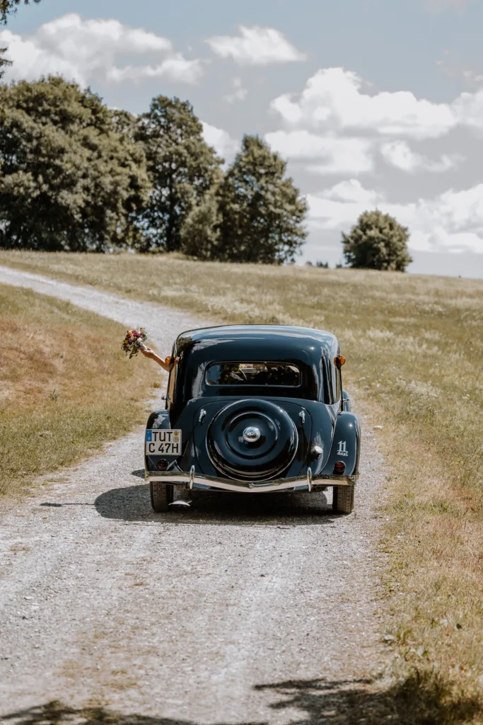 Kuss des Brautpaares im Oldtimer nach der Trauung