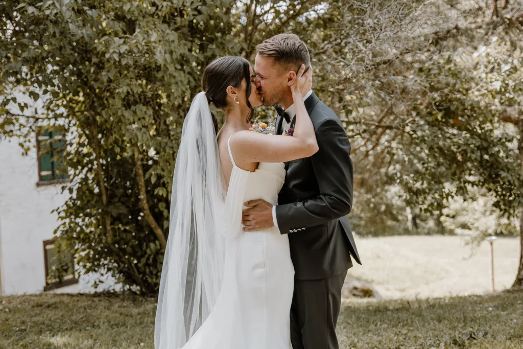 Brautpaar küsst sich nach der Trauung unter Bäumen bei Rottweil.