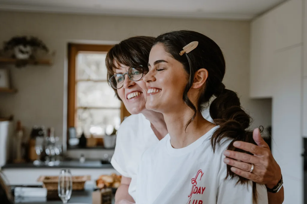 Braut lacht gemeinsam mit ihrer Mutter beim Getting Ready
