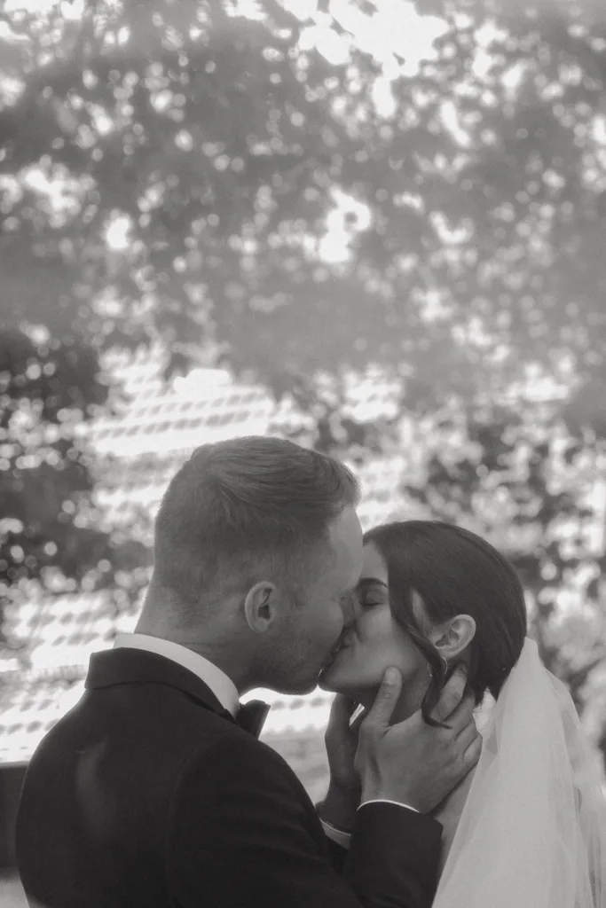 Schwarzweißaufnahme eines innigen Kusses des Brautpaares