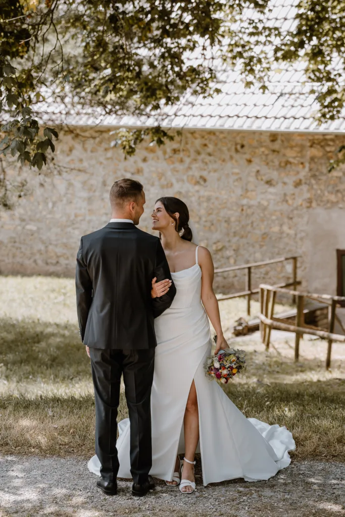 Brautpaar geht Arm in Arm über eine Wiese