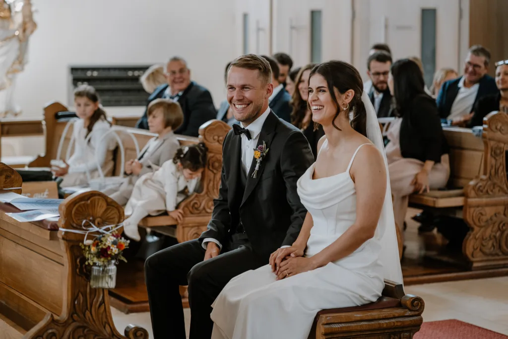 lachendes Brautpaar vor dem Altar