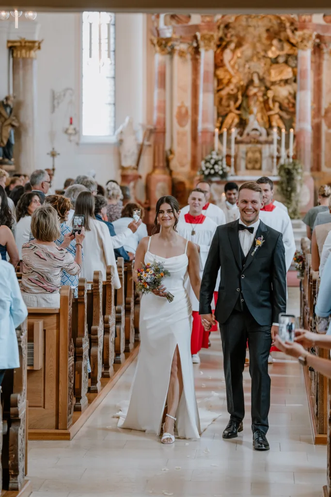 Brautpaar läuft Hand in Hand aus der Kirche