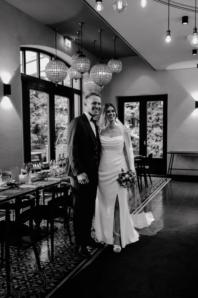 Brautpaar steht lächelnd gemeinsam in der Hochzeitslocation die Säge in Niedereschach