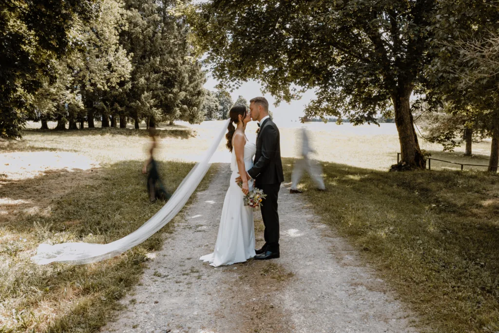 Brautpaar küsst sich auf einem Feldweg bei Rottweil, der Schleier liegt im Gras.