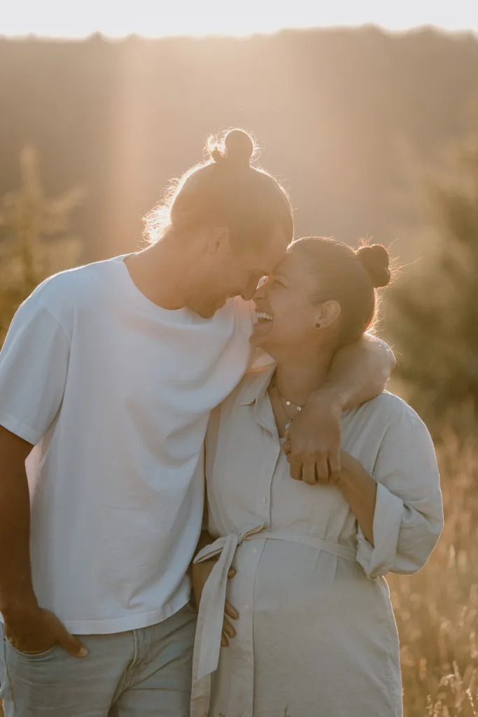 Werdende Eltern berühren sich Stirn an Stirn bei der Babybauchfotografie im warmen Abendlicht
