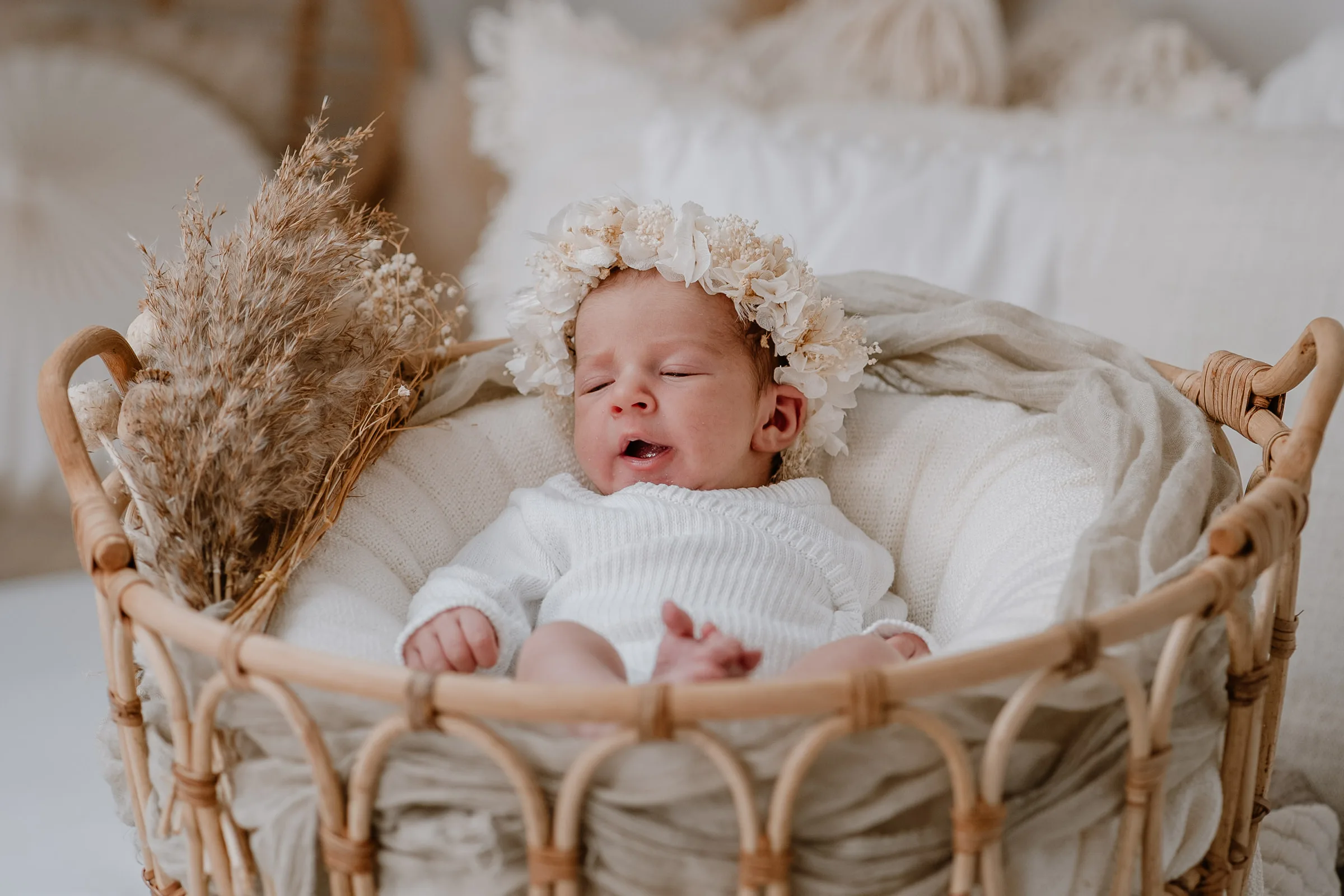 Neugeborenes liegt ruhig im Korb bei der Neugeborenenfotografie mit natürlichen Materialien